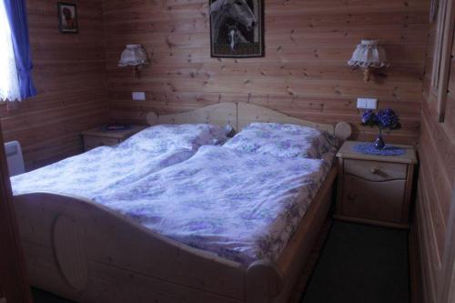 a large bed in a room with wooden walls at Ferienhaus-Kuenzel in Viechtach