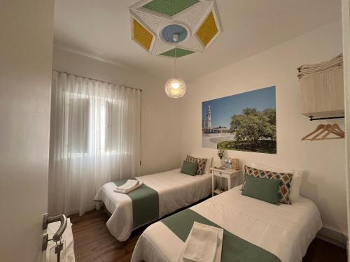 a room with two beds and a chandelier at Casa do Ti Luís in Leiria
