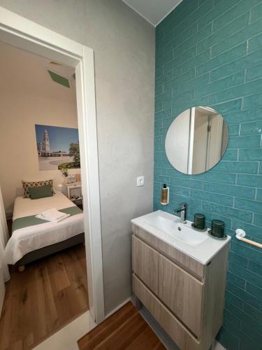 a bathroom with a sink and a mirror and a bed at Casa do Ti Luís in Leiria