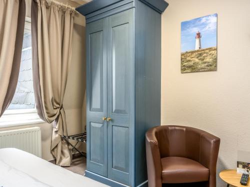 ein Schlafzimmer mit einer blauen Tür, einem Stuhl und einem Leuchtturm in der Unterkunft PLAZA Premium Sylt in Wenningstedt-Braderup