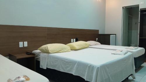 two beds with white sheets and pillows in a room at Center Plaza Hotel in São Paulo