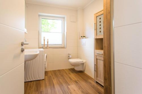 a bathroom with a toilet and a sink and a window at Feriendomizil-SeeSand in Gammendorf