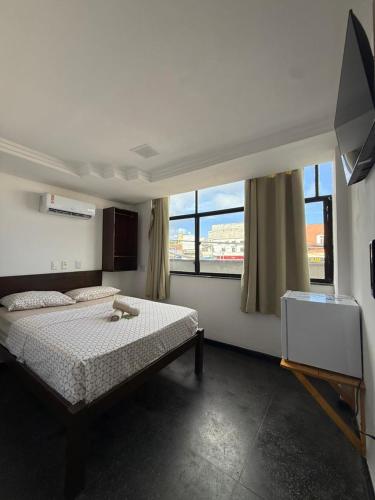 a bedroom with a bed and a tv and windows at Hotel Bela Vista in Salvador