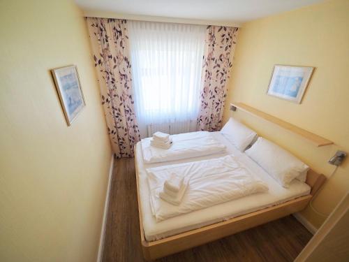 a small bedroom with a white bed with a window at Appartement-124 in Westerland