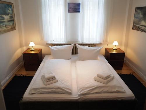 a bedroom with a large white bed with two night stands at Haus-Bockelmann in Westerland