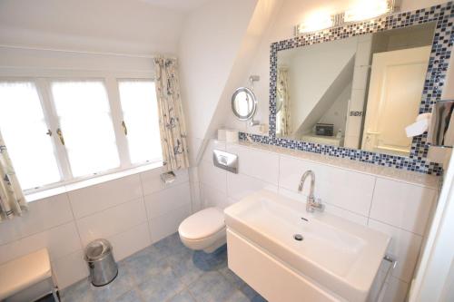 a bathroom with a sink and a toilet and a mirror at Haus-Neumann in Westerland