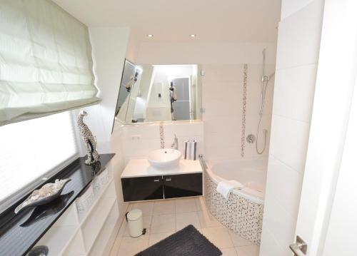 a white bathroom with a sink and a tub at Syltstyle-12 in Tinnum