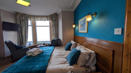 a bedroom with a large bed with a blue wall at Sunnyside House in Rothesay
