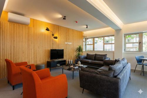 a living room with a couch and orange chairs at Oporto City View - Guest House Suites in Porto
