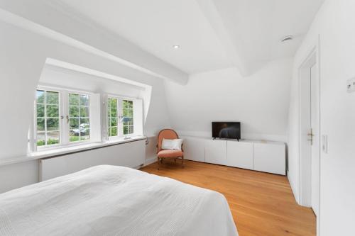 a white bedroom with a bed and a tv at Carolinenhof-2 in Tinnum