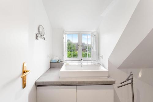 a white bathroom with a tub and a window at Carolinenhof-2 in Tinnum