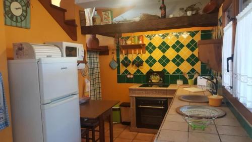 a kitchen with a white refrigerator and a table at Casa El Pajar De Tasio in San Miguel del Pino