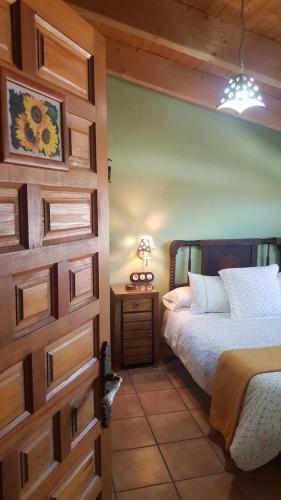 a bedroom with a bed and a wooden door at Casa El Pajar De Tasio in San Miguel del Pino