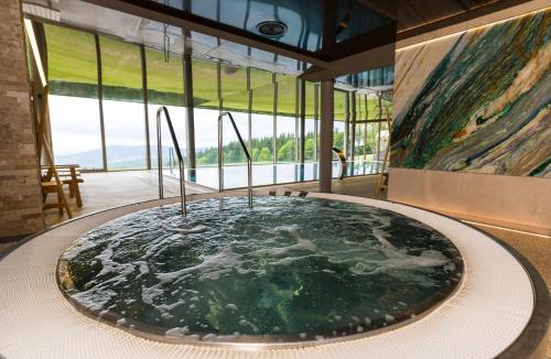 a hot tub in the middle of a room with windows at Hotel Tetřeví Boudy in Pec pod Sněžkou