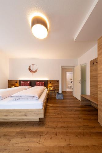 a bedroom with a large bed and wooden floors at Pension Hofer in Brunico