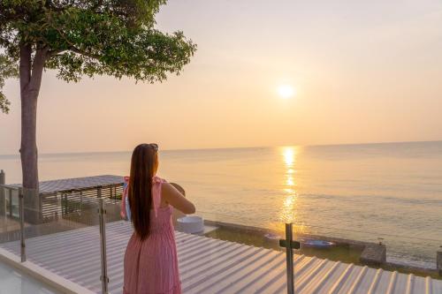 a woman looking out over the ocean at the sunset at Pailay Beachfront Villa Cha-Am in Ban Bang Ket