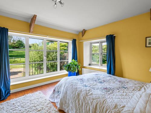a bedroom with yellow walls and a bed and windows at Chantry in Kingsbridge
