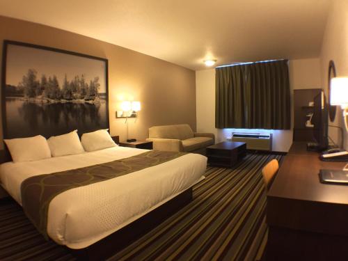 a hotel room with a large bed and a desk at Super 8 by Wyndham Kenora in Kenora