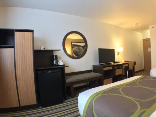 a hotel room with a bed and a desk and a mirror at Super 8 by Wyndham Kenora in Kenora