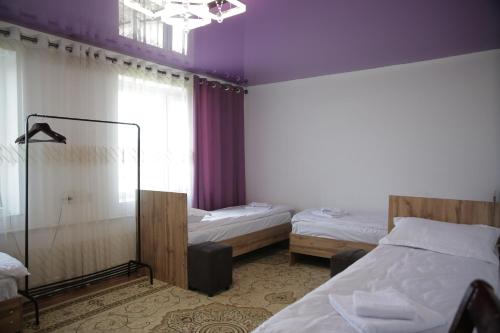 a bedroom with two beds and a window with purple ceilings at Central Guest House Karakol in Karakol