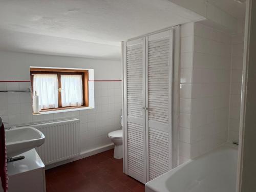 a white bathroom with a toilet and a sink at Nusshof in Berchtesgaden