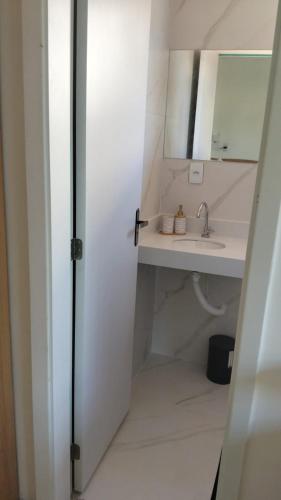 a white bathroom with a sink and a mirror at Casa da Dinda 203 in Rio das Ostras