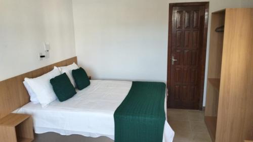 a bedroom with a bed with green and white pillows at Casa da Dinda 203 in Rio das Ostras