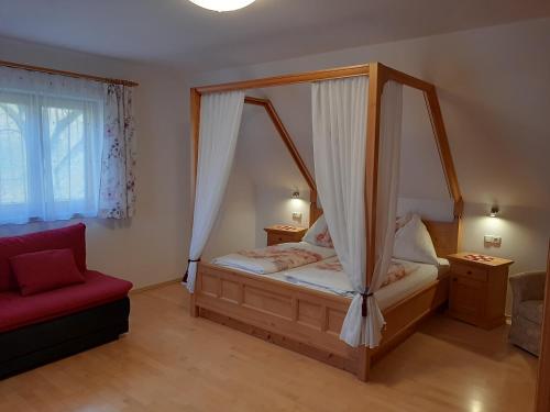 a bedroom with a canopy bed and a red chair at Ferienhaus Zotter in Feldbach