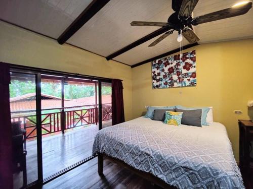 a bedroom with a bed with a ceiling fan and a balcony at Ocean Breeze Beach Front Apartment with AC in Puerto Viejo