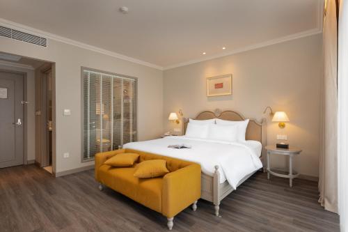a bedroom with a large white bed and a yellow chair at Hotel Montmartre de Sapa - Newly Opened April 2026 in Sapa