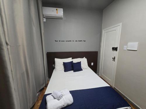 a bedroom with a bed with blue and white pillows at Hotel Divinopolis Center in Divinópolis
