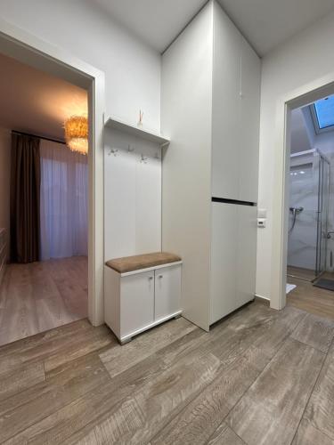 a kitchen with white walls and wood floors and a refrigerator at The View Apartment Bușteni in Buşteni