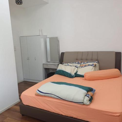 a bed with an orange blanket and pillows on it at Sunway Onsen Apartment Tambun by ELK Homestay in Tambun