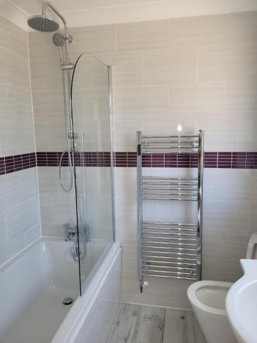 a bathroom with a shower and a tub and a sink at Pebble Beach, ground floor 1 bedroom flat in Chichester
