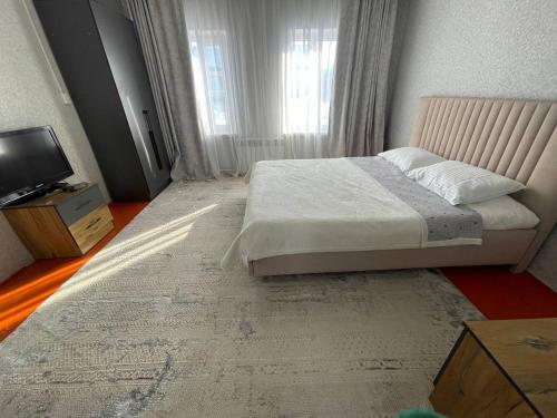 a bedroom with a large bed and a television at Hanbiike in Karakol