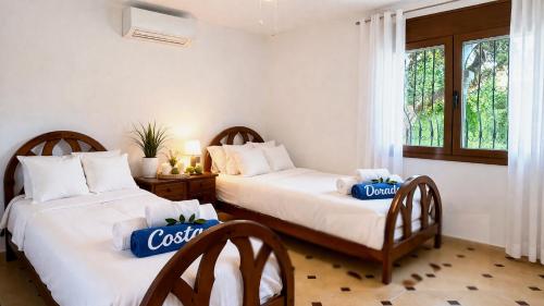 two beds in a room with two chairs and a window at villa PLAYA RUSTICAL in Miami Platja