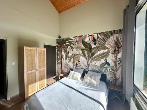 a bedroom with a bed with a tropical wallpaper at Villa Ongizatea au calme avec piscine et vue montagne in Urrugne
