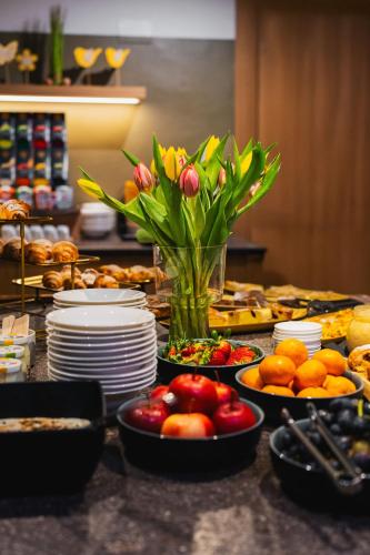 a table with plates and fruits and flowers in a vase at Hotel Sachsenklemme in Fortezza