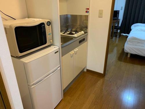 a kitchen with a microwave on top of a refrigerator at AO Dazaifu / Vacation STAY 61718 in Chikushino