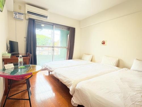 two beds in a room with a table and a window at AO Dazaifu / Vacation STAY 61718 in Chikushino