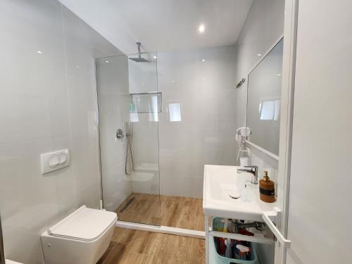 a white bathroom with a toilet and a shower at Viola Apartments 2 Min to Beach in Vlorë