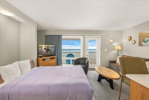 a bedroom with a large bed and a living room at Oceanfront King Suite - Beach Access - Pool and Hot Tub in Lincoln City