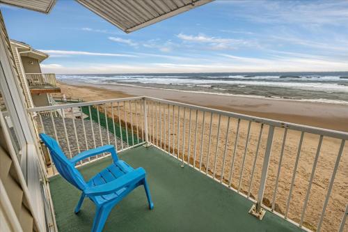 a blue chair sitting on a balcony overlooking the beach at Oceanfront King Suite - Beach Access - Pool and Hot Tub in Lincoln City