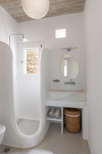 a white bathroom with a sink and a mirror at Villa Petra in Andros