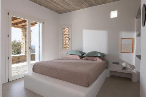 a bedroom with a bed and a large window at Villa Petra in Andros