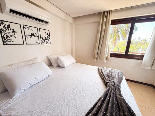 a bedroom with a white bed with a window at Kariri beach apt 427 Praia do Cumbuco in Cumbuco