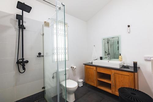 a bathroom with a shower and a toilet and a sink at Bahari Villa Beachfront in Port Louis