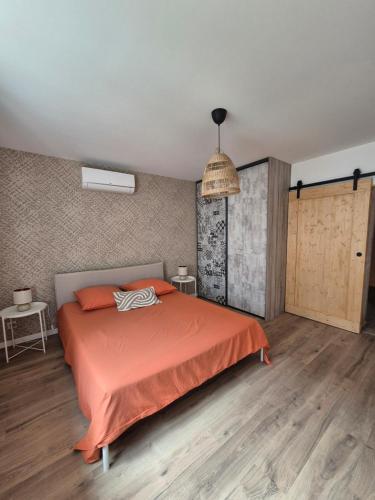 a bedroom with a bed with an orange comforter at La place in Pont-de-Vaux