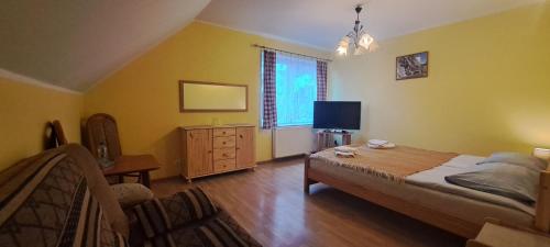 a bedroom with a bed and a dresser and a television at Willa Pod Jedlicą in Ciechocinek