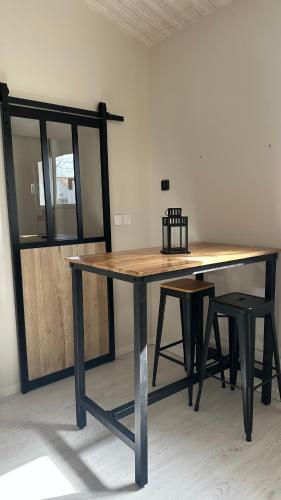 a large wooden table with two stools and a table and chairs at Chambre spacieuse et moderne in Sallertaine